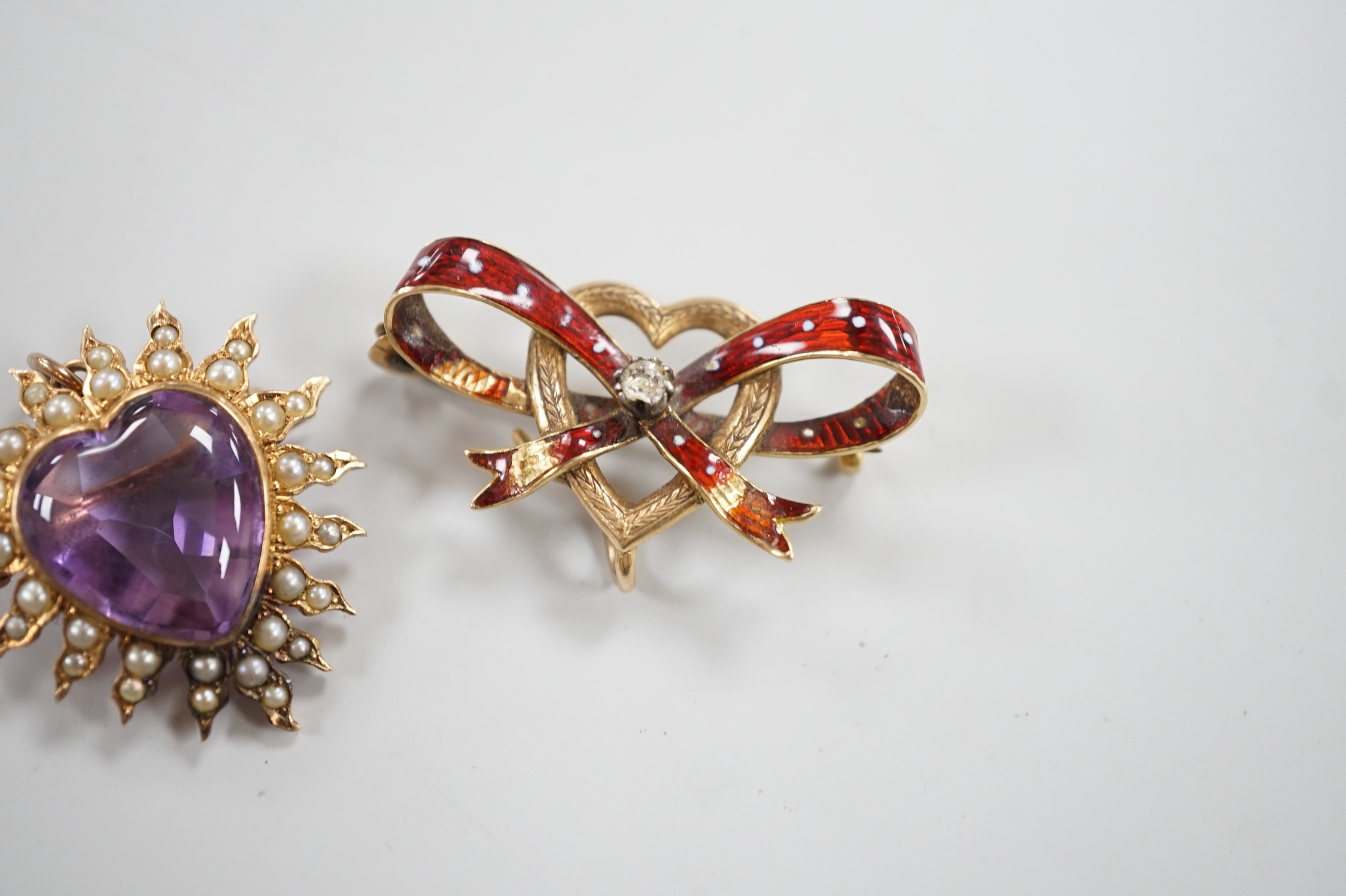 An early 20th century yellow metal amethyst and seed peart set heart shaped pendant brooch, 25mm, gross 5.3 grams and a yellow metal and enamel set ribbon bow and heart brooch (enamel a.f.).